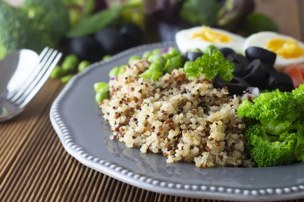 Quinoa salad with green pea,broccoli, olives. Healthy food, lunch over wooden background. Vegetarian food.