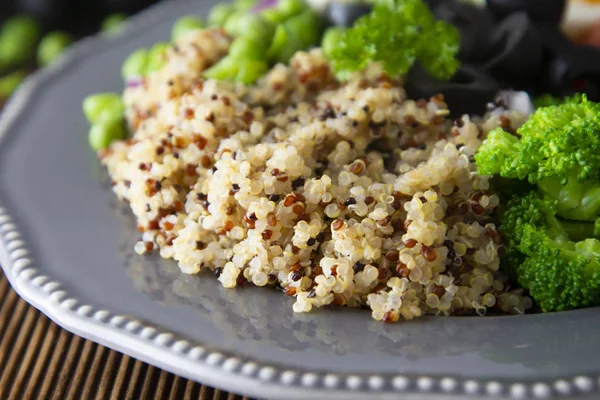 Quinoa salad with green pea,broccoli, olives. Healthy food, lunch over wooden background. Vegetarian food.