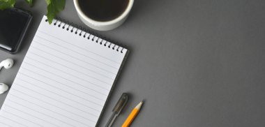 Resepsiyon çalışma alanı, gri çalışma alanıyla fincan kahve, boş defter ve bitki karanlık masada. Fincan kahve ve metin için yer. düz lay.