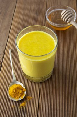 Zerdeçal altın süt. Sağlıklı içecek zerdeçal ve bal ile yaptı. Birçok hastalık için ilaç. Rustik ahşap arka plan.