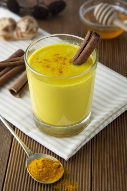 Zerdeçal altın süt. Sağlıklı içecek zerdeçal bal ve tarçın ile yaptı. Birçok hastalık için ilaç. Rustik ahşap arka plan.