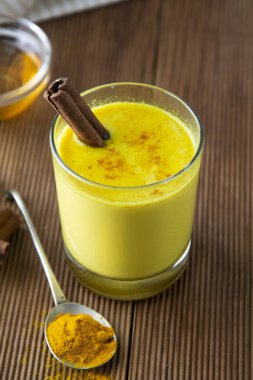 Zerdeçal altın süt. Sağlıklı içecek zerdeçal bal ve tarçın ile yaptı. Birçok hastalık için ilaç. Rustik ahşap arka plan.