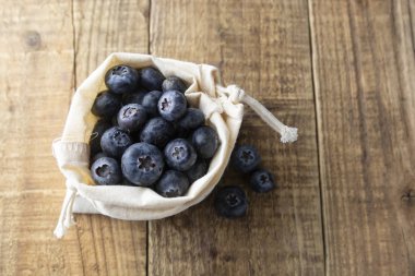 Sıfır bel kavramı, hiçbir plastik. Kahverengi bir tekstil, rustik ahşap masa üzerinden eko çanta dışarı dökülmesini yaban mersini. Eko Dostu meyveler, meyve. Biyo berry.