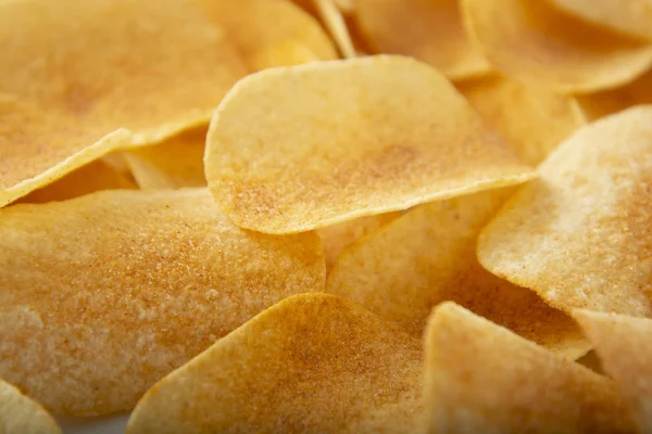 Background golden potato chips texture. Crispy unhealthy snack isolated.