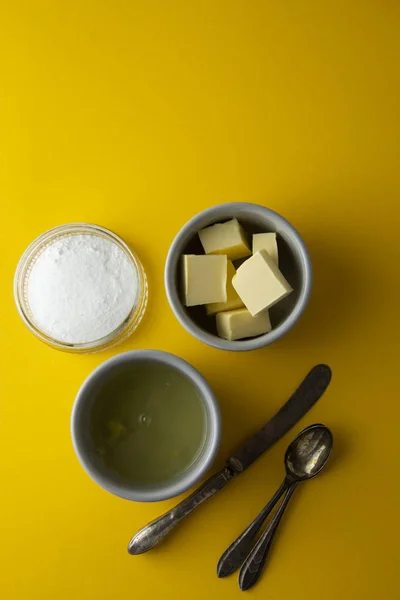 Ingredients frame for baking pastry or dessert - butter, flour, eggs, milk, sugar. Yellow background, flat lay. Dessert recipe, cooking process. Copy space.
