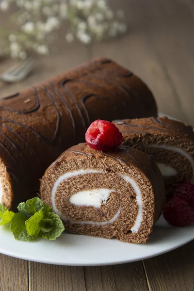 Delicioso bolo de esponja de rolo de chocolate com creme de baunilha e folhas de hortelã. Comida doce do deserto . — Fotografia de Stock