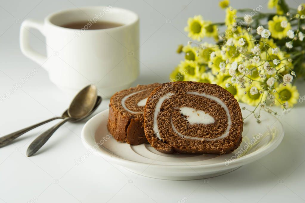 Swiss roll chocolate cake chocolate with cream. Dessert. Breakfast coffee cup and cake. Light background.