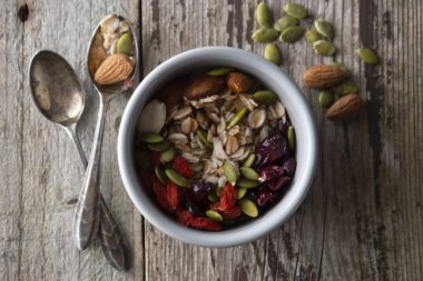 Sağlıklı kahvaltı. Yulaf, fındık ve kurutulmuş meyve-elma, reçineler, Kabak tohumları ve ahşap masada badem ile iki kase müsli. Üst görünüm. Rustik tarzı.