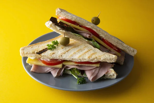 Sándwich club con jamón aislado. Panini doble tostado con jamón, queso y verduras frescas. Fondo amarillo . — Foto de Stock