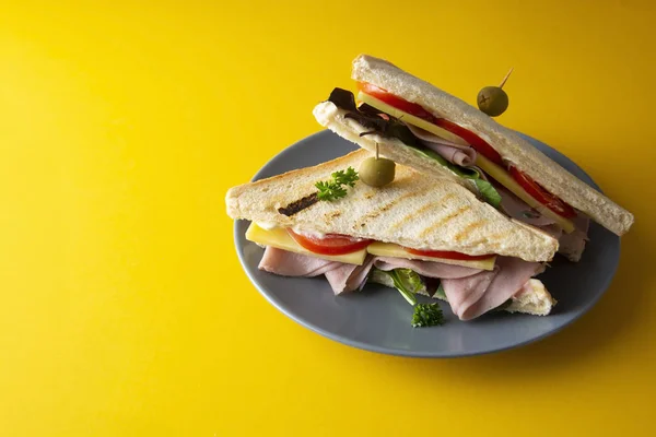 Sándwich club con jamón aislado. Panini doble tostado con jamón, queso y verduras frescas. Fondo amarillo . — Foto de Stock