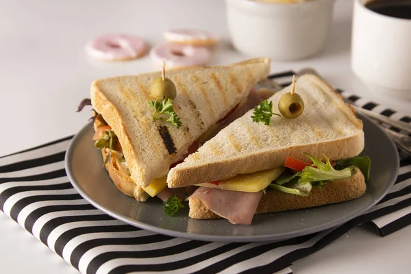 Stylish sandwich. Toasted double panini with ham, cheese fresh vegetables. Snack at work or lunch. Light background. — Stock Photo, Image