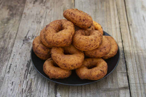 Donat buatan sendiri. bulat, lingkaran donat lezat di piring hitam, latar belakang kayu. Makanan penutup atau sarapan. Salin ruang . — Stok Foto