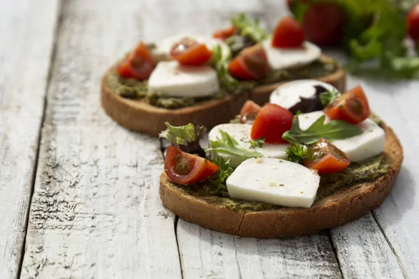 Healthy food. Toast sandwich with mozzarella, cherry tomatoes and pesto, light wooden background. Healthy breakfast, snack. Copy space