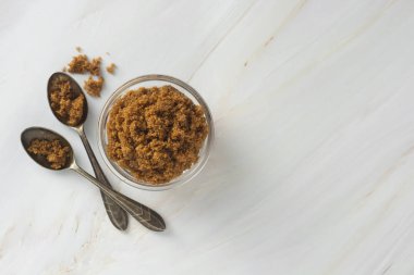 Kahverengi şeker cam kase izole, tarz mermer arka plan üzerinde. Üst görünüm, kopyalama alanı.