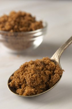 Metal kaşık kahverengi şeker parlak, mermer arka plan kopya alanı ile. Tatlı maddesi, şeker bağımlısı. Kopyalama alanı.