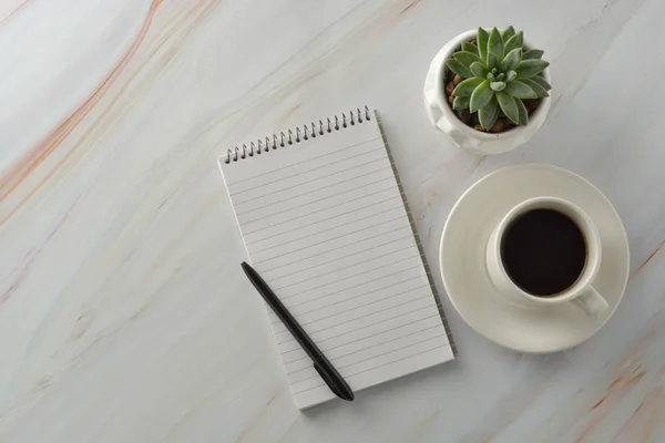 Cuaderno abierto con taza de café, planta suculenta sobre escritorio de mármol. Lugar de trabajo, mesa de trabajo. Vista superior . — Foto de Stock