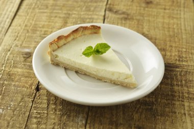 Ahşap masa üzerinde düz cheesecake dilim. Ev yapımı tatlı.