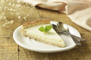 Ahşap masa üzerinde düz cheesecake dilim. Ev yapımı tatlı.