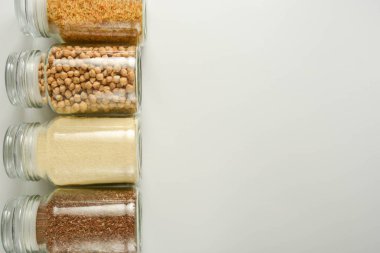 Sıfır atık kavramı. Cam kavanozda çeşitli çiğ tahıllar. Yiyecek deposu. Düz yatıyordu. Beyaz arka plan.