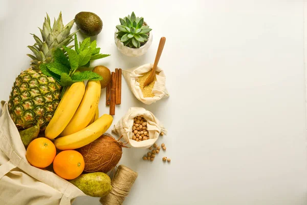 Zero waste food storage. Fruits and cereals in eco textile bags, white background. Copy space.