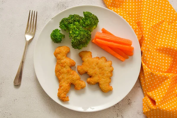Детская еда. наггетсы с овощами. Курица в форме динозавра, рыба или наггетсы индейки, готовые к употреблению . — стоковое фото
