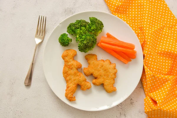 Kids food. nuggets with vegetables. Dinosaur shaped chicken, fish or turkey nuggets, ready to eat. — Stock Photo, Image