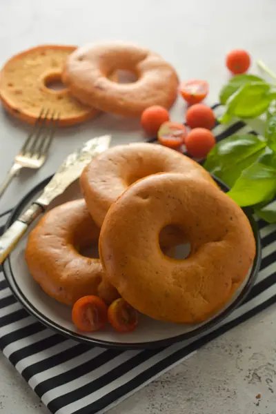 Bagels geïsoleerd op heldere bord met basilicum en cherry tomaten voor het ontbijt. Gebak. — Stockfoto