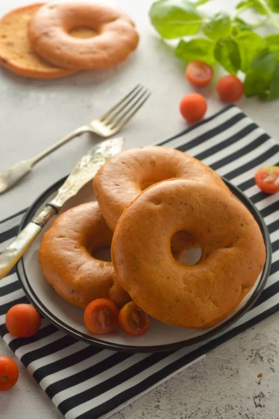 Bagels geïsoleerd op heldere bord met basilicum en cherry tomaten voor het ontbijt. Gebak. — Stockfoto