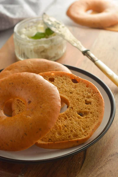 Heerlijke bagels met roomkaas op houten bord, gebak brood voor het ontbijt. — Stockfoto