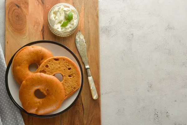 Deliciosos bagels com queijo creme em tábua de madeira, pão de pastelaria para o café da manhã. Vista superior. Espaço de cópia . — Fotografia de Stock