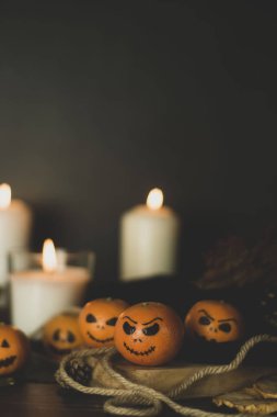 Mutlu Cadılar Bayramı narenciye, mandalina korkutucu, komik yüzleri ile boyanmış. Mumlu karanlık fotoğraf. Geleneksel Cadılar Bayramı kabaklarına alternatifler.