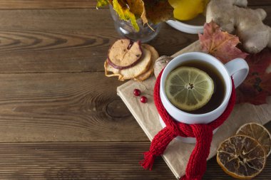 Ballı ve limonlu zencefil çayı. Kırmızı fularlı çay bardağı. Sonbahar veya kış ılık içecek. Ahşap arka plan.