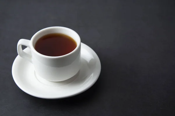 Uma xícara de chá preto isolado sobre fundo escuro com espaço de cópia . — Fotografia de Stock
