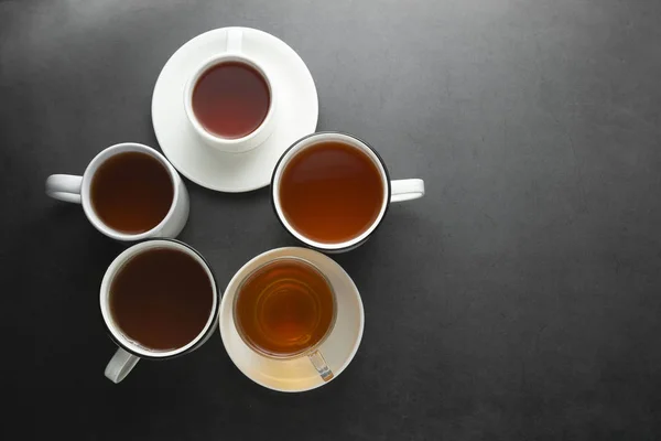 Felülnézet sok csésze, bögrék forró tea ital a sötét háttér, másolási tér. Tea idő vagy tea fék. Őszi ital. Tónusú kép teáscsészék. — Stock Fotó