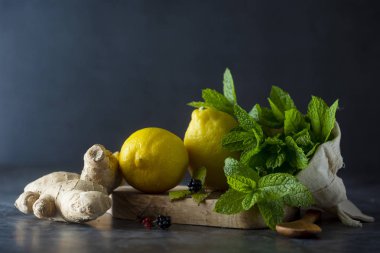 Zencefil, limon ve nane yaprakları koyu arka planda. Zencefil çayı, içecek maddeleri, soğuk ve sonbahar saati.