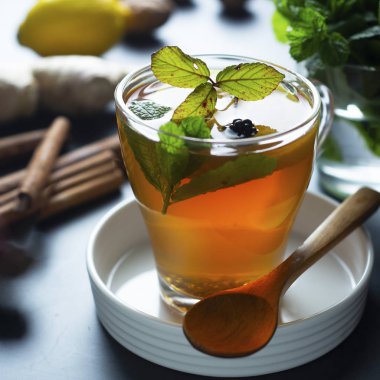 Koyu arka planda limon ve nane yaprakları ile zencefil çay Cam fincan. Kare görüntü, soğuk ve sonbahar saati.