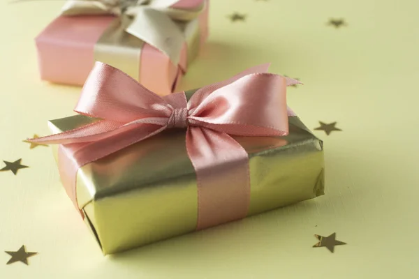 Goldene und rosa Geschenkbox isoliert auf gelbem Hintergrund. Geburtstag, Weihnachtsfeier aufgesetzt. — Stockfoto