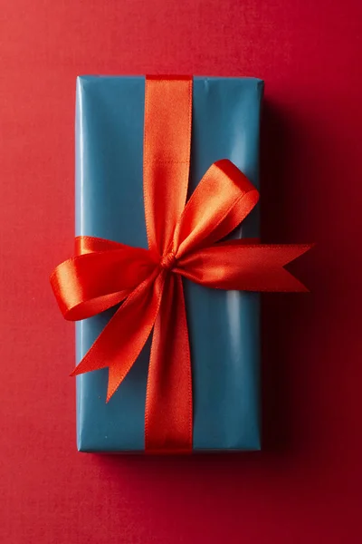 蓝色礼品盒与红色丝带和蝴蝶结隔离在红色背景，顶视图。基督， 派对概念. — 图库照片