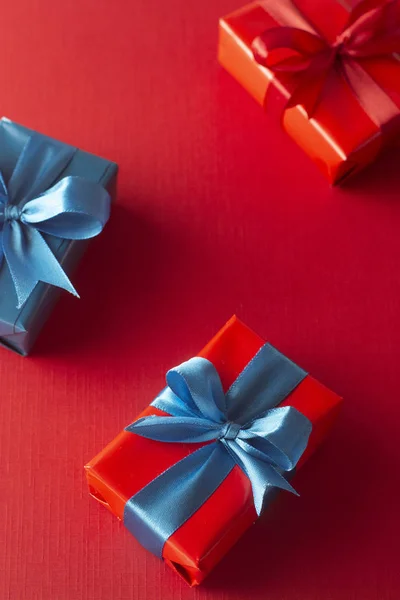 Coffrets cadeaux bleus et rouges avec ruban rouge et arc isolé sur fond rouge, vue de dessus. Noël, concept de fête . — Photo