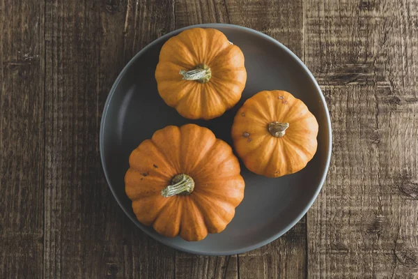 Осенний День благодарения с апельсиновой тыквой в тарелке деревенский деревянный фон — стоковое фото