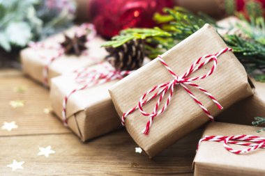 El sanatları kağıdına sarılı Noel hediye kutuları, köknar dalları, kırmızı takılar, ahşap masa üzerindeki çam kozalakları bayram bayramını kutlamak için hazırlandı..
