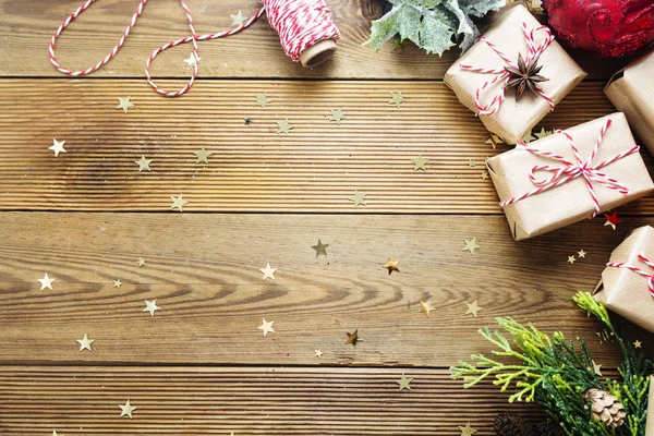 圣诞模拟，礼品盒包裹在手工纸盒中，冷杉枝条，红色的灌木丛，木制桌子上的松果，节假日。 复制空间. — 图库照片