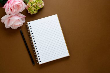 Kadınsı bir geçmişi var. Çiçekli boş defter - güller, ortancalar. Kahverengi arka plan, üst manzara.