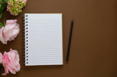 Çiçekli bir defter aç - güller, ortancalar. Kahverengi arka plan. Üst görünüm.