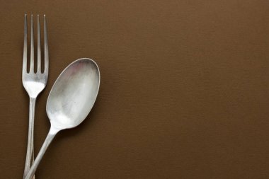 Kaşık ve çatalı kapat, klasik çatal bıçak takımı kahverengi arkaplanı izole et, mesaj için yeri kopyala. Yemek, tarif menüsü maketi.