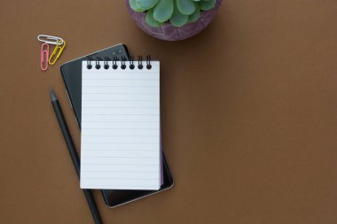 Çalışma alanı açık defter ve kahverengi arkaplan üzerinde akıllı telefon, metin için kopyalama alanı. Evden çalış..