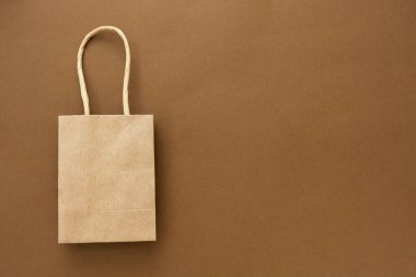 Kahverengi arkaplanda izole edilmiş kağıt çanta, metin için kopyalama alanı.