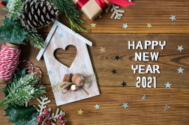 Mutlu yıllar 2021 kelimeleriyle Noel arkaplanı kırmızı hediye kutuları, köknar dalları, ahşap ev ve ahşap arka planda kış süslemeleri.
