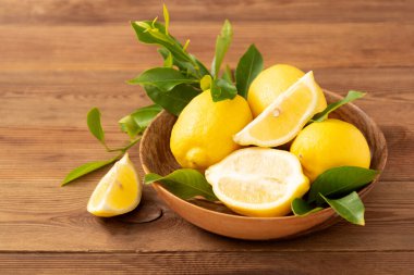 Kaba ahşap arka plandaki limonlar yeşil yapraklı Citrus meyveleri..
