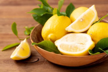 Kaba ahşap arka plandaki limonlar yeşil yapraklı Citrus meyveleri..
